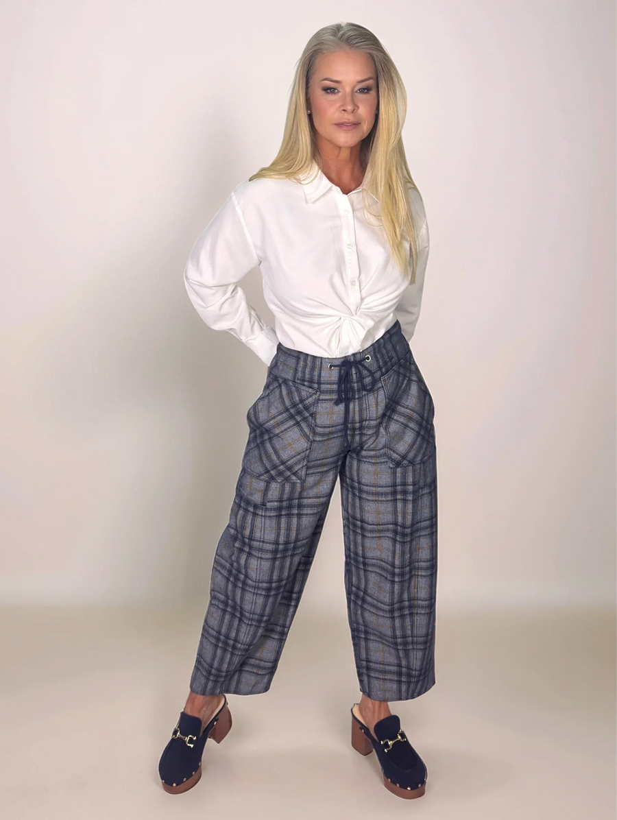 Woman wearing a white blouse and plaid pants against a plain background