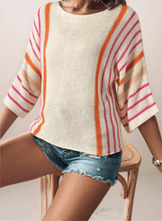 a woman wearing a cream lightweight sweater that has orange and hot pink vertical stripes from shoulder and down the arm. The sleeves are wide and are drop shoulder