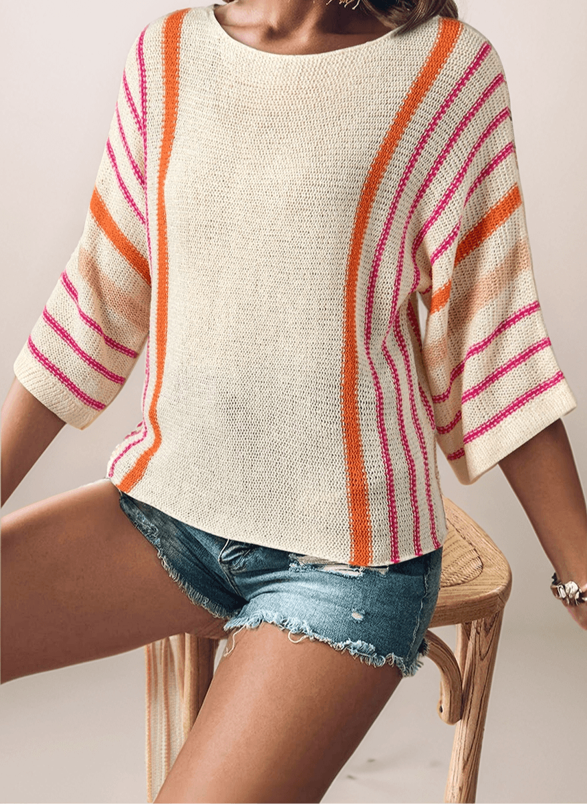 a woman wearing a cream lightweight sweater that has orange and hot pink vertical stripes from shoulder and down the arm. The sleeves are wide and are drop shoulder