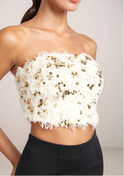 White strapless top with gold sequins worn by a model against a neutral background