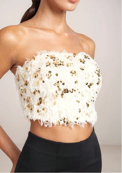 White strapless top with gold sequins worn by a model against a neutral background
