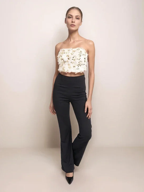 Model wearing a white floral top and black pants on a beige background