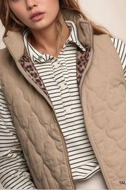 Person wearing a beige quilted vest over a striped shirt with leopard print lining.