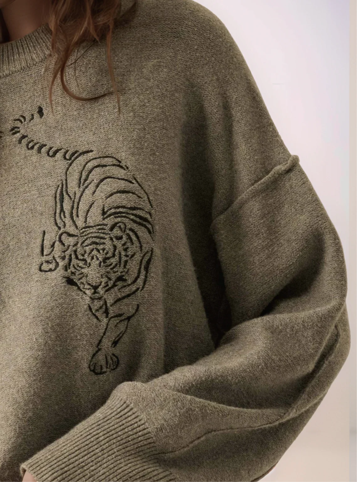 Gray sweater with a black tiger design on a plain background