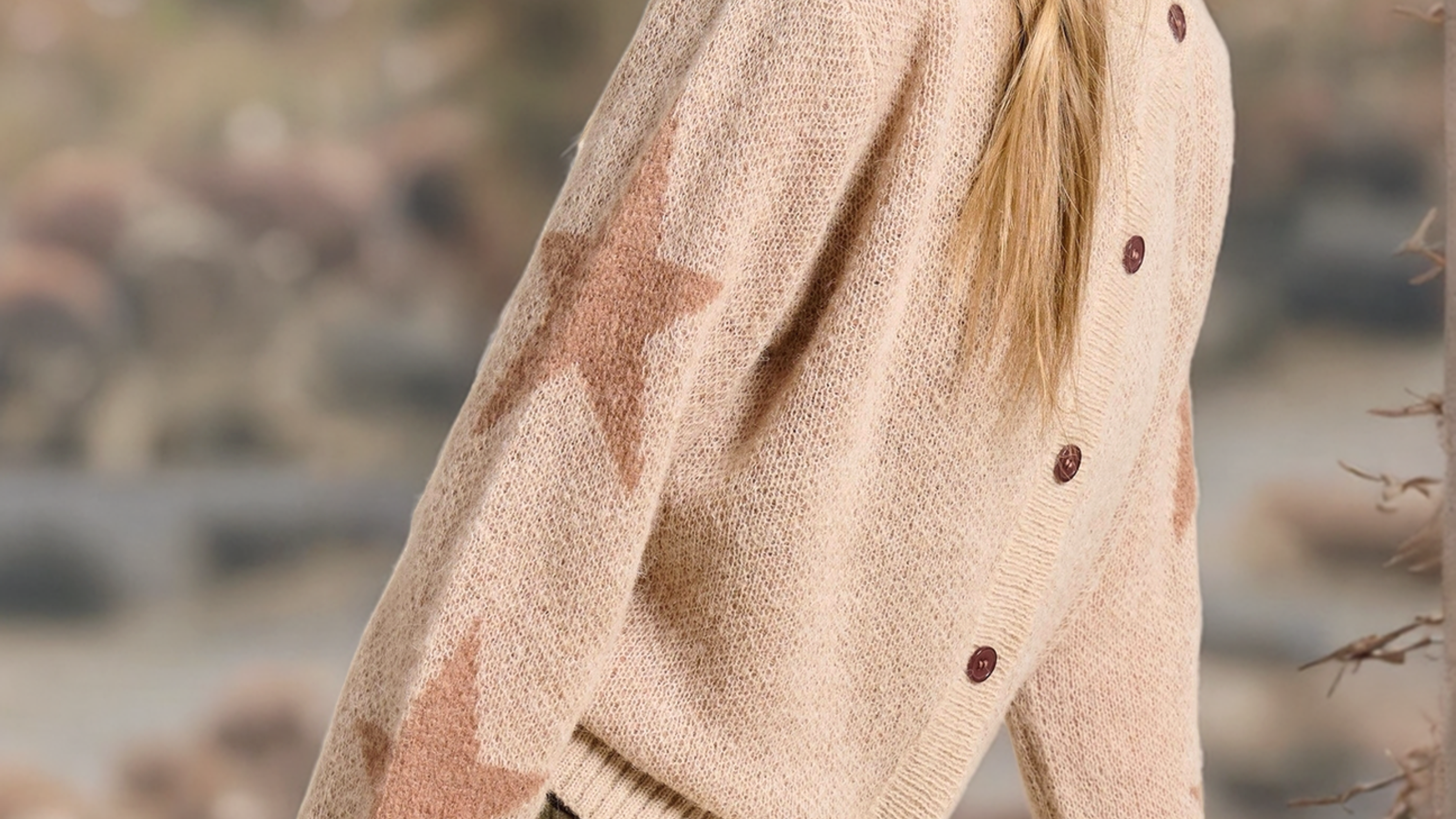Person wearing a beige cardigan with buttons in a natural setting