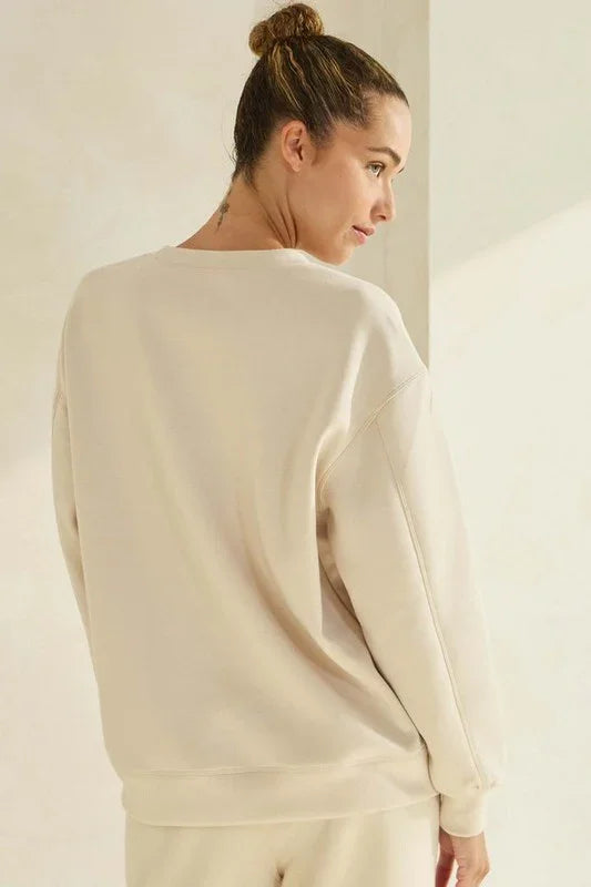 Woman wearing a beige sweater against a plain background