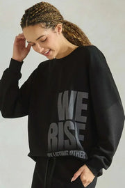 Person wearing a black sweatshirt with 'WE RISE' text on a plain background