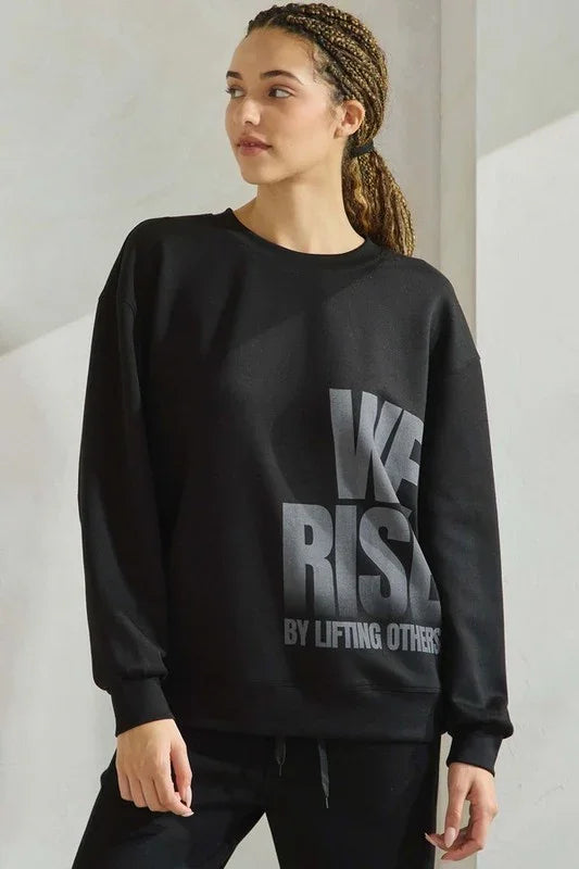 Person wearing a black sweatshirt with text, standing against a plain background