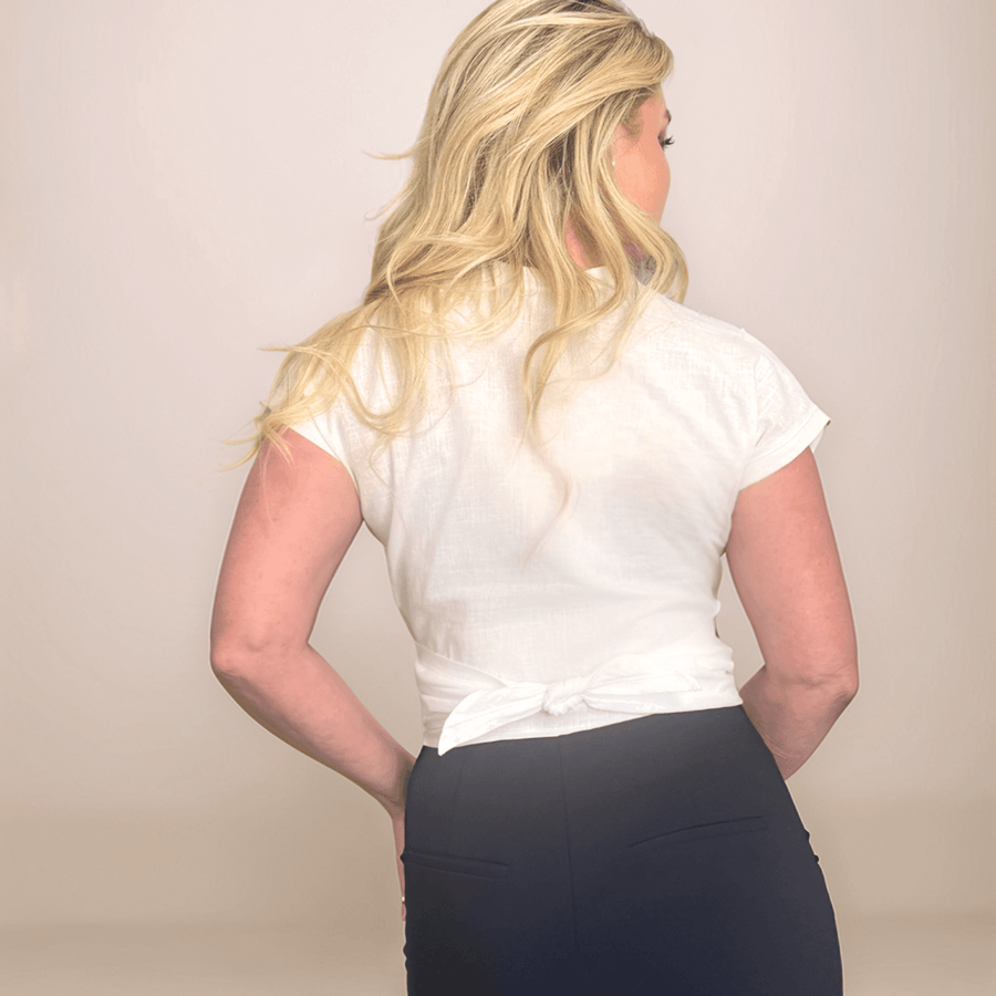 a blonde woman is wearing a white wrap top that is tied in the back.