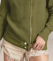 Woman wearing a green ribbed sweater with a zipper on a plain background