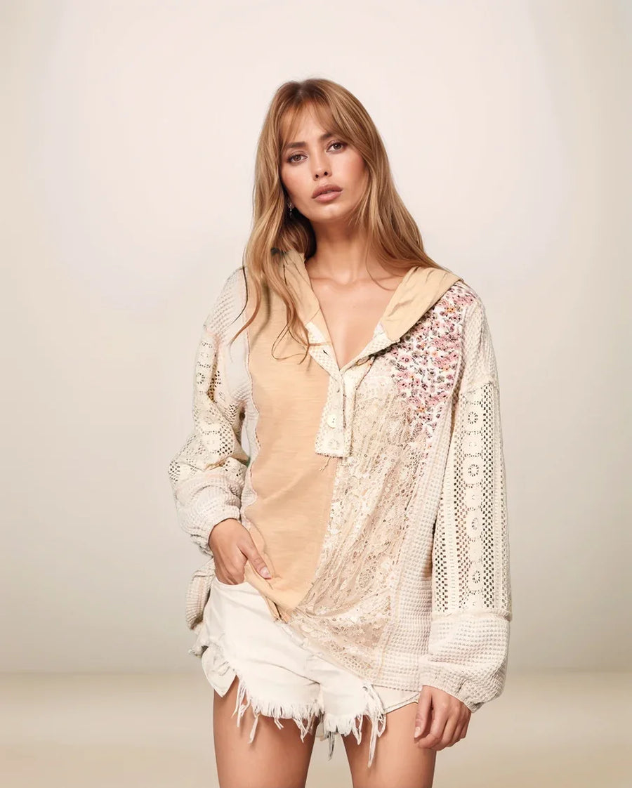 Woman wearing a beige top and white lace cover-up against a plain background