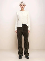 Person wearing a white jacket and brown corduroy pants on a plain background