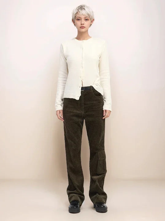 Person wearing a white jacket and brown corduroy pants on a plain background