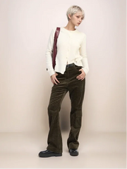 Person wearing a white sweater and dark pants with a maroon bag on a plain background