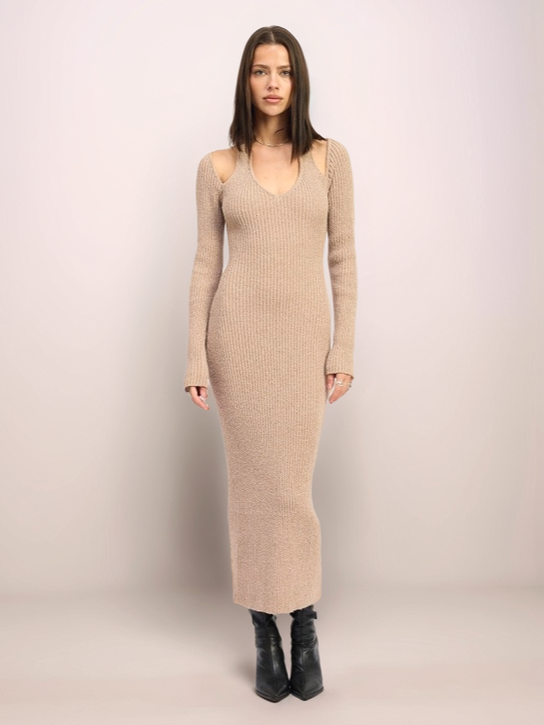 Woman wearing a beige ribbed dress against a plain background