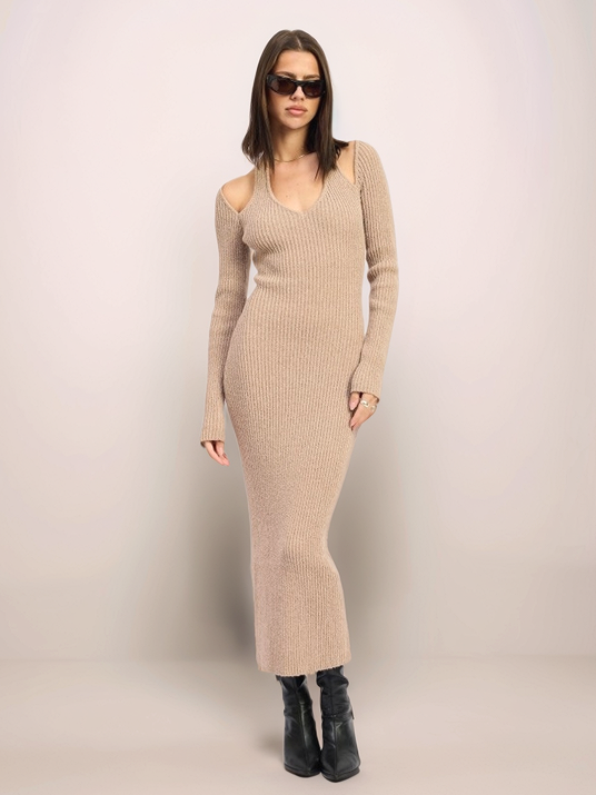 Woman wearing a beige ribbed dress against a plain background