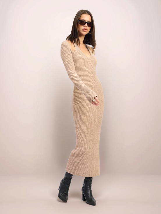 Woman wearing a beige long-sleeve dress against a plain background