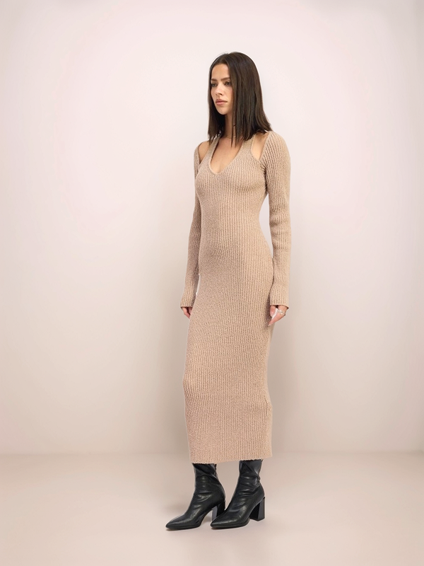 Woman wearing a beige ribbed dress against a plain background