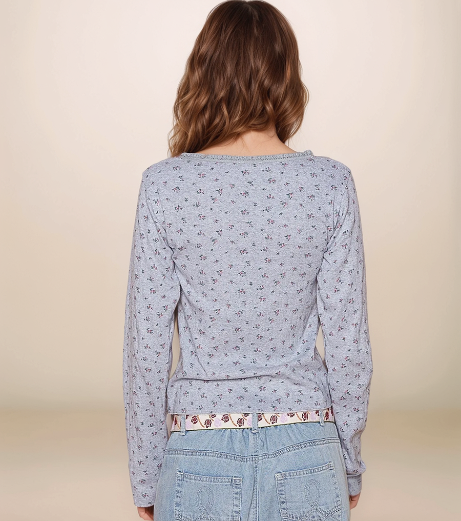 Person wearing a light blue floral-patterned long-sleeve shirt with a beige background