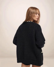 Woman wearing a black oversized sweater against a plain background