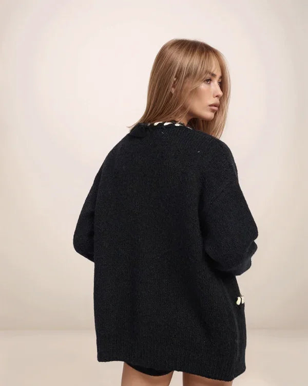 Woman wearing a black oversized sweater against a plain background