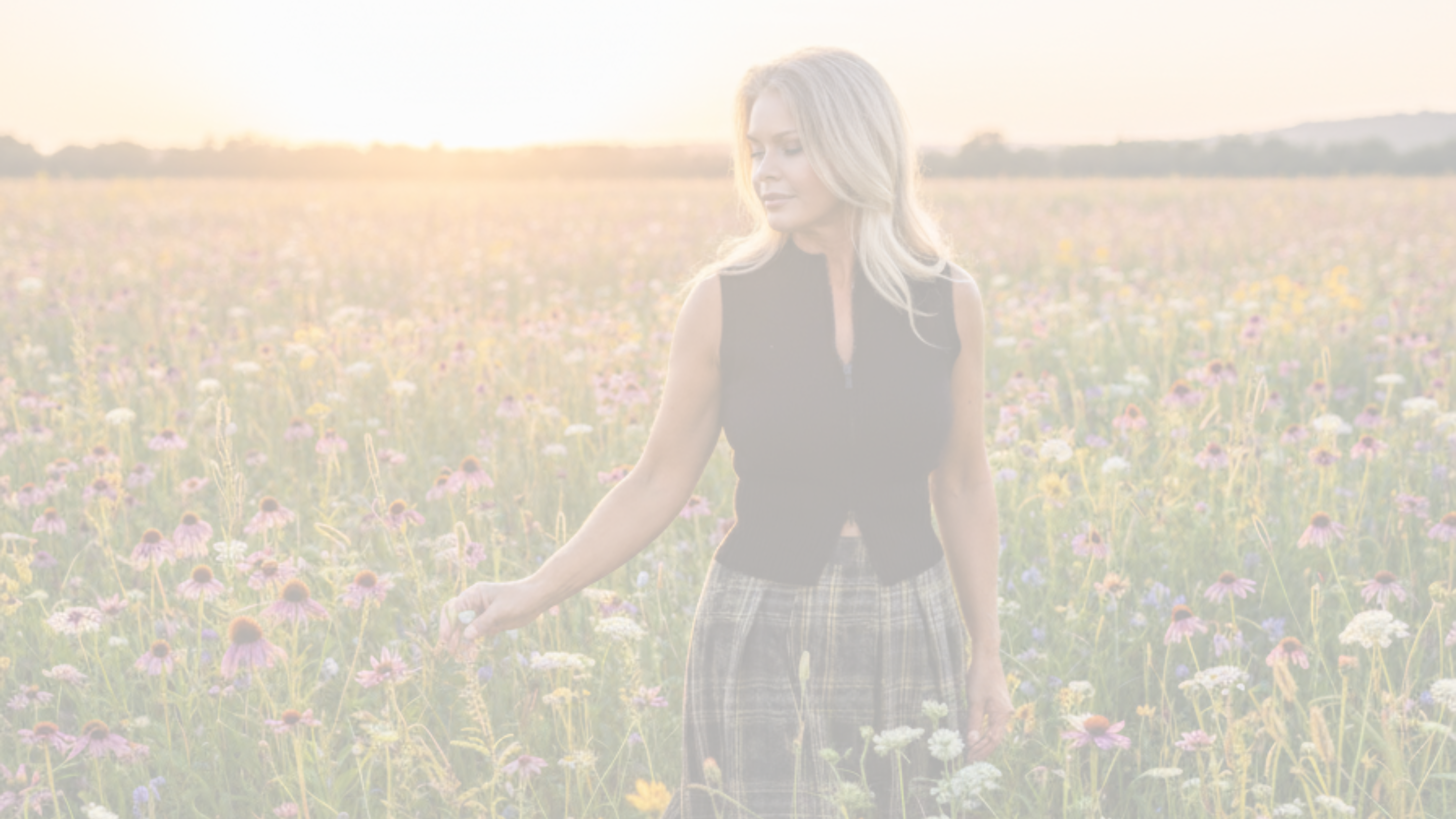 Woman standing in a field of wildflowers with a warm glow