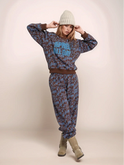 Person wearing a patterned sweater and pants with a beanie on a plain background