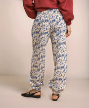 Person wearing blue and white patterned pants with a red top on a beige background