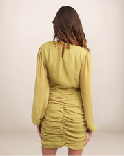 Woman wearing a green dress with long sleeves on a plain background