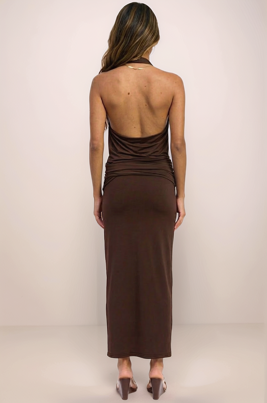 A full-length back view of the Aurelia set in espresso brown, featuring the dramatic architectural open-back halter top and the coordinating smoothing maxi skirt. The high-stretch nylon-spandex blend provides a sleek, body-con silhouette that flows into a maxi hem for a sophisticated evening look.