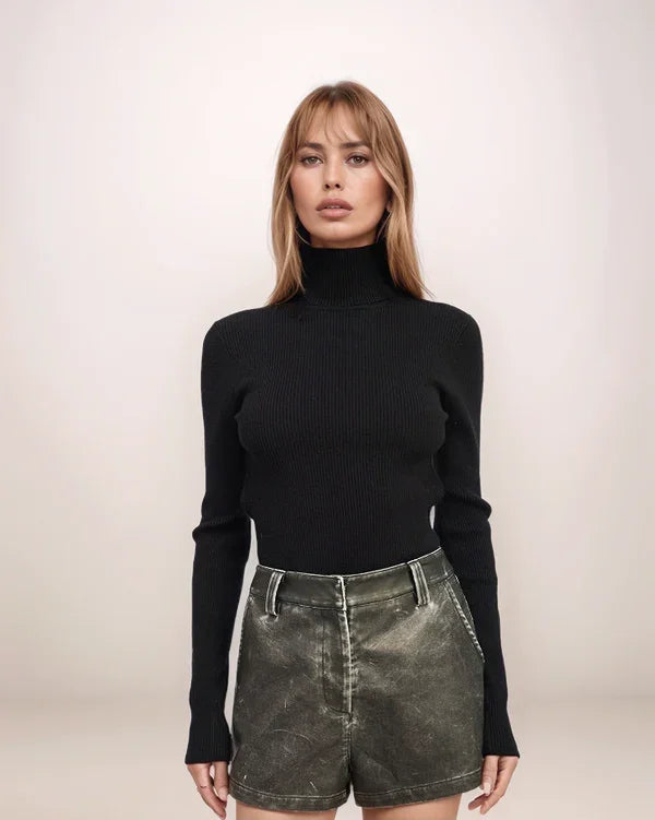 Person wearing a black turtleneck and green shorts on a plain background