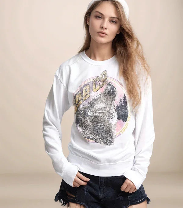 Woman wearing a white sweatshirt with a graphic design on a beige background