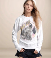 Woman wearing a white sweatshirt with a graphic design on a beige background