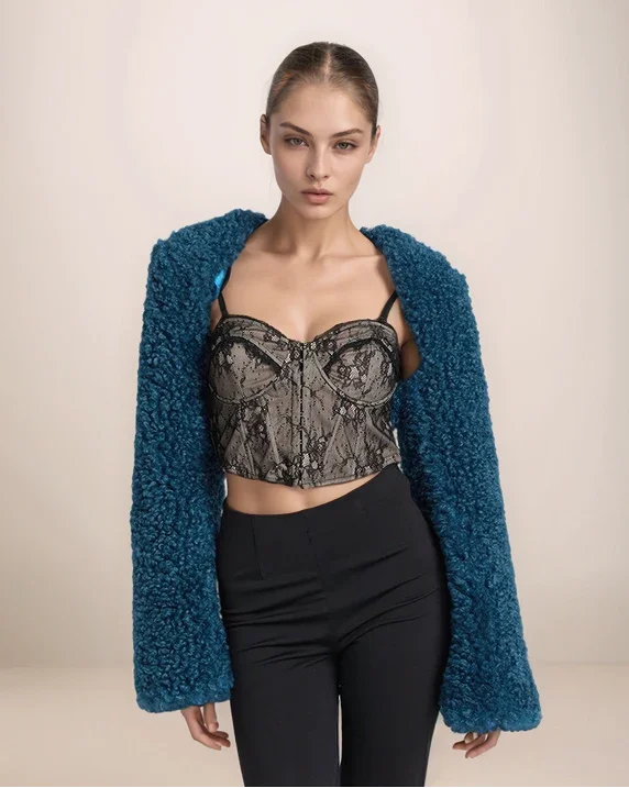 Model wearing a blue textured cardigan, black lace top, and black pants on a beige background