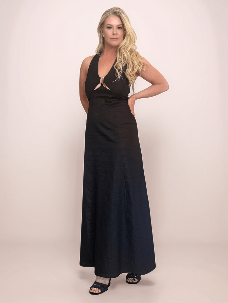A blonde woman wearing a black linen halter cutout maxi dress with a gold ring detail at the bust. Perfect for summer events and resort wear