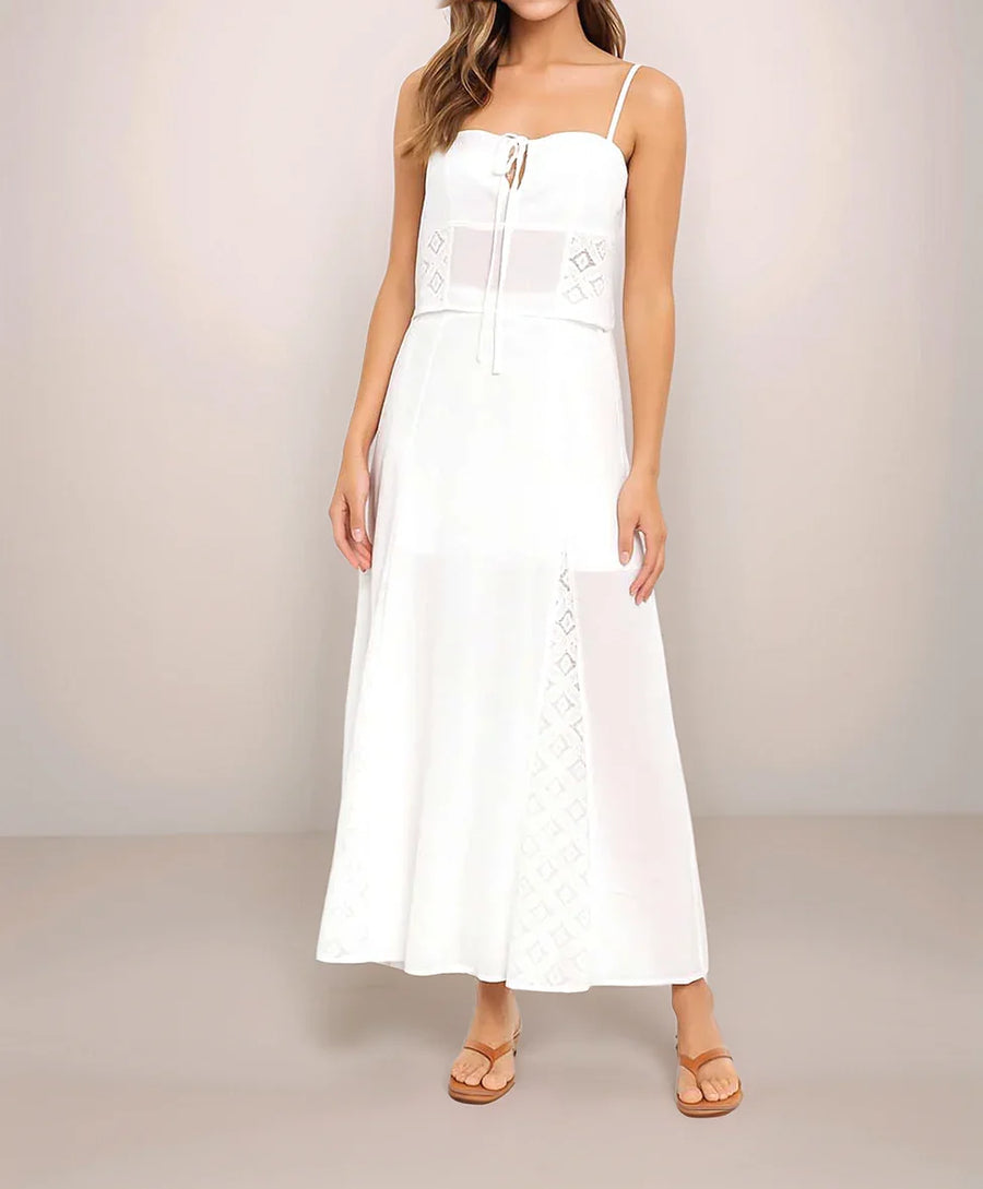 White dress with thin straps worn by a person on a plain background