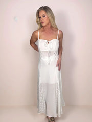 a blonde woman is wearing a breezy white, cotton camisole and matching maxi skirt that features diamond lace inserts.