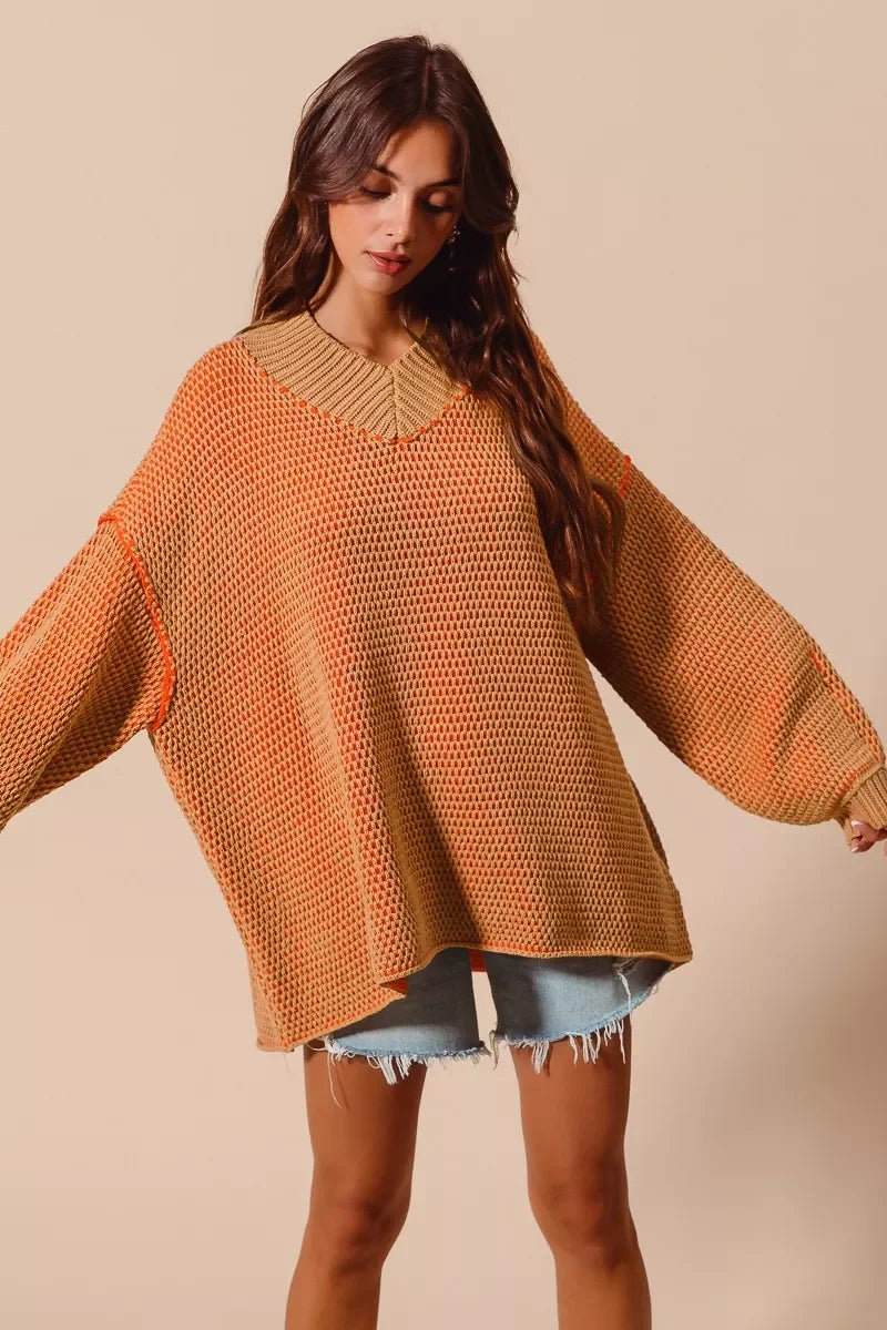 Woman wearing a large orange knitted sweater against a beige background