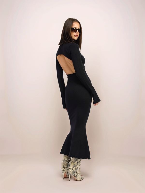 Woman wearing a black dress with cut-out design on a plain background