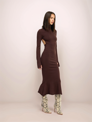 Woman wearing a brown dress with cut-out design on a plain background