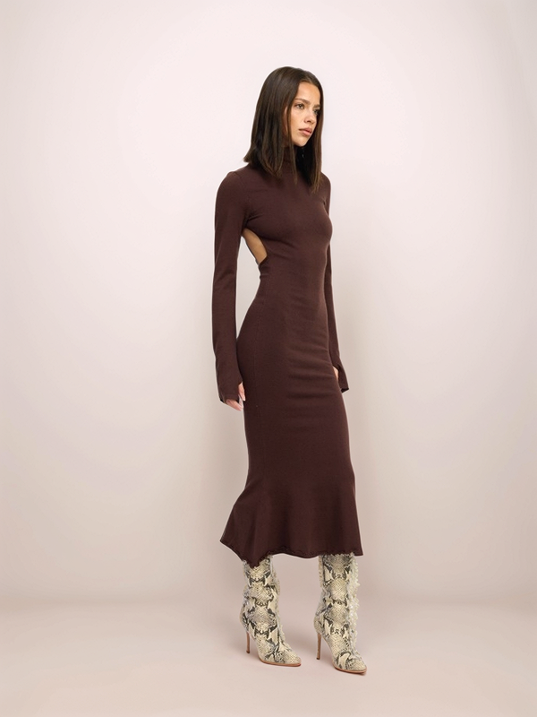 Woman wearing a brown dress with cut-out design on a plain background