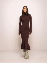 Woman wearing a brown long-sleeve dress with a fitted silhouette on a plain background
