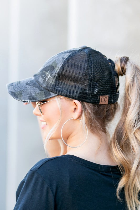 Person wearing a black mesh cap with a brand logo, standing against a light background