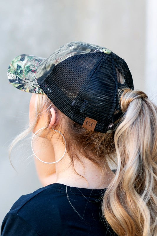 Person wearing a black trucker hat with floral visor and visible brand logo.
