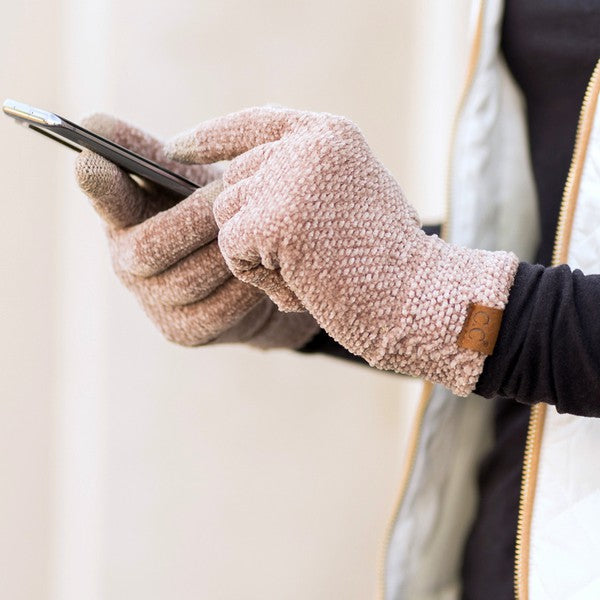 Person wearing fuzzy gloves holding a phone with a neutral background