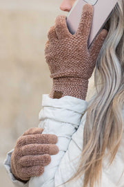 Close-up of a person wearing brown fuzzy gloves with a blurred background