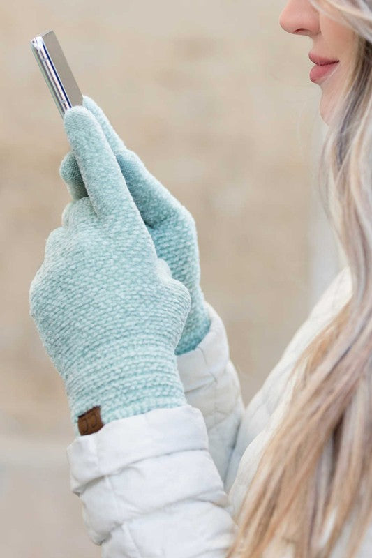 Person wearing mint colored gloves holding a phone with a neutral background