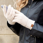 Person wearing white gloves holding a phone, with a dark jacket and blurred background
