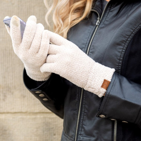 Person wearing white gloves holding a phone, with a dark jacket and blurred background