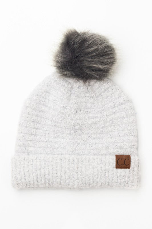 White knit beanie with gray fur pom-pom on a white background